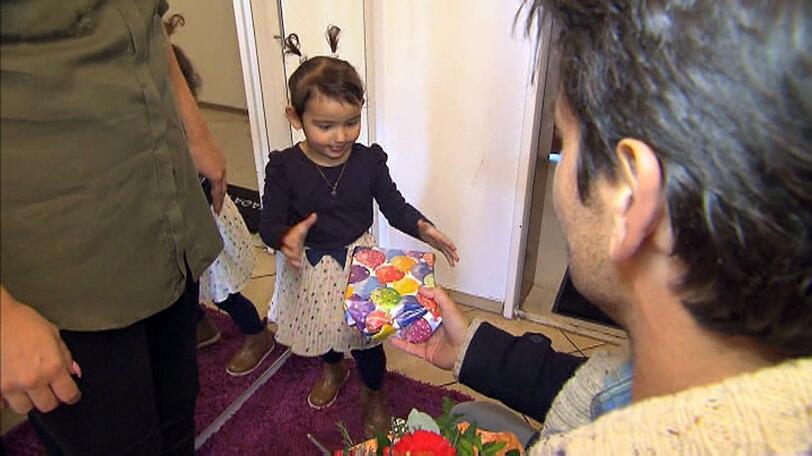 Der Bachelor bringt beim Home-Date Sarahs kleinen Tochter ein Geschenk mit.
