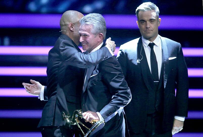 Pep Guardiola und Jupp Heynckes. Im Hintergrund steht Robbie Williams.