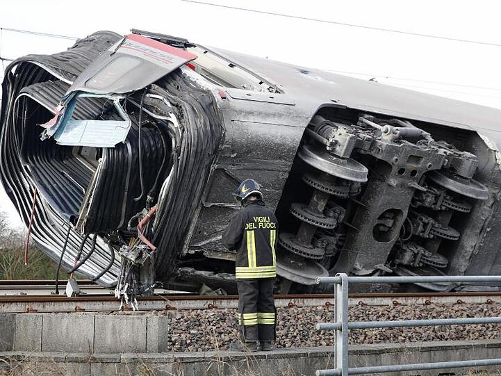Ein Feuerwehrmann vor einem entgleisten Zugwaggon. Mehrere Waggons sollen sich überschlagen haben.