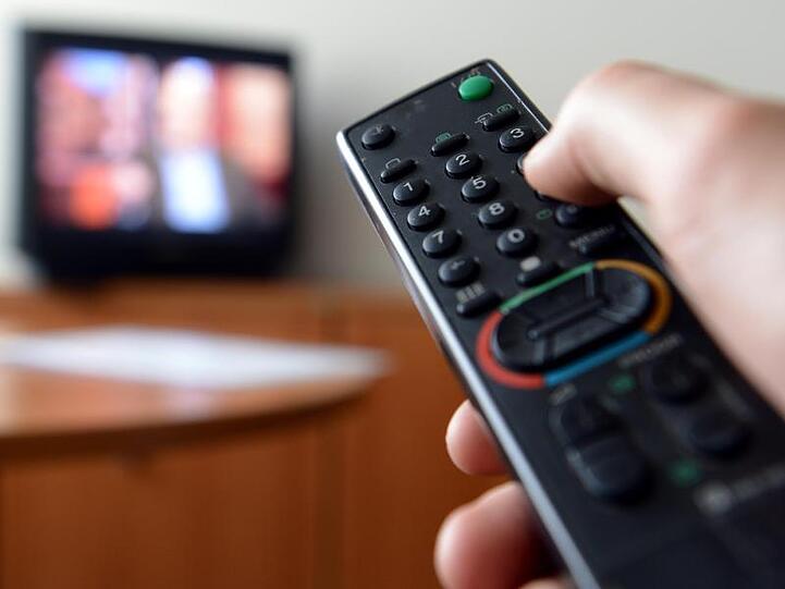 Eine Hand hält eine Fernbedienung für ein Fernsehgerät.