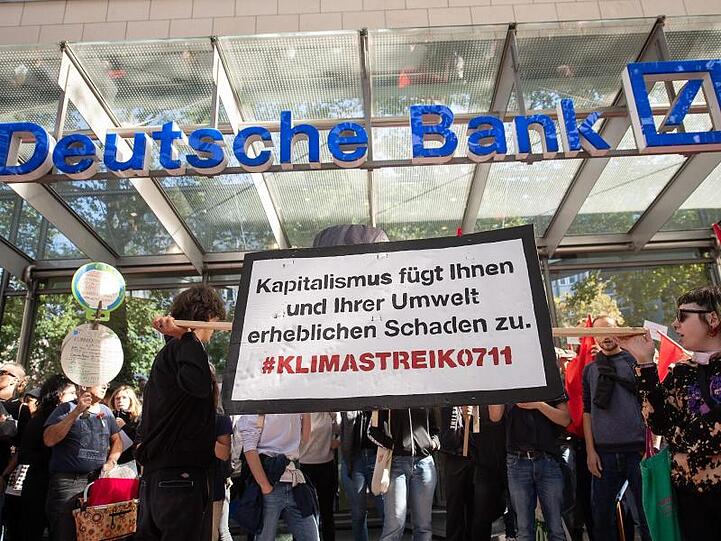"Kapitalismus fügt Ihnen und Ihrer Umwelt erheblichen Schaden zu." Demonstranten blockieren in Stuttgart den Eingang einer Filiale der Deutschen Bank.
