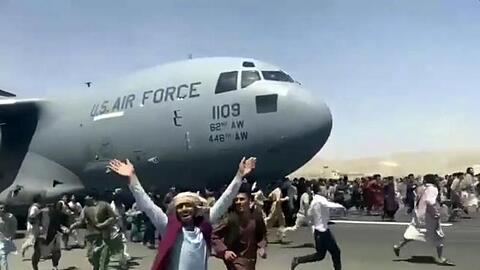 Zahlreiche Menschen sind auf dem Rollfeld des Kabul International Airport unterwegs.