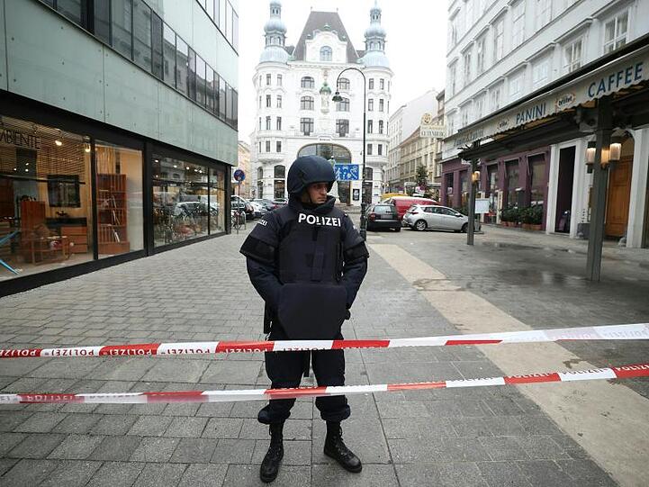 Ein Polizist steht am Tatort in der Wiener Innenstadt hinter einem Absperrband.