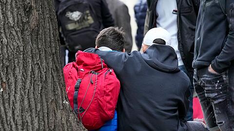 Zwei Kinder nehmen sich in einem abgesperrten Bereich der Schule in den Arm.