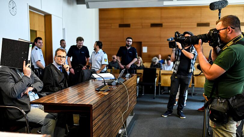 Der wegen Kindesmissbrauchs Angeklagte Knut S. sitzt mit einem Aktenordner vor dem Gesicht im Saal des Landgerichts neben seinem Anwalt Holger Meier.