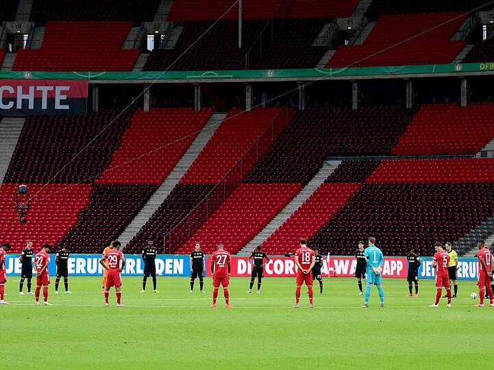 Die Spieler beider Mannschaften (München in rotem Trikot) gedenken den Opfern der Corona-Pandemie. Foto: Robert Michael/dpa-Zentralbild/Pool/dpa