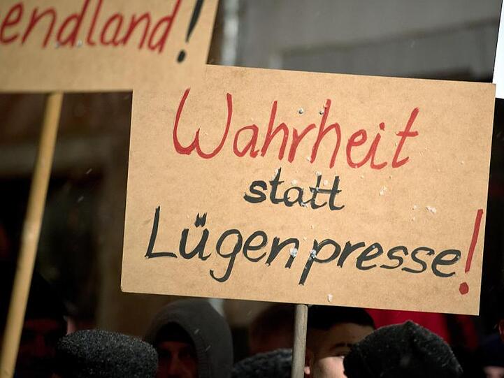 Pegida-Anhänger halten ein Schild mit der Aufschrift "Wahrheit statt Lügenpresse!" hoch.