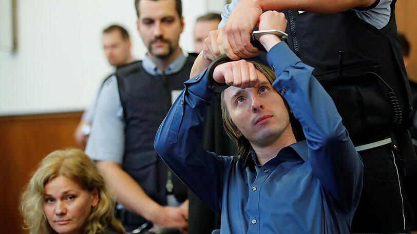 Ein Justizvollzugsbeamter nimmt im Landgericht in Dortmund dem Angeklagten Sergej W. die Handschellen ab. Dem 28-jährigen Mann wird 28-facher versuchter Mord vorgeworfen. Er soll am 11. April in der Nähe des Team-Hotels eine Sprengstoffanschlag auf den Mannschaftsbus von Borussia Dortmund verübt haben.
