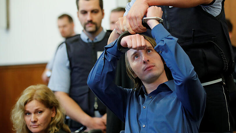 Ein Justizvollzugsbeamter nimmt im Landgericht in Dortmund dem Angeklagten Sergej W. die Handschellen ab. Dem 28-jährigen Mann wird 28-facher versuchter Mord vorgeworfen. Er soll am 11. April in der Nähe des Team-Hotels eine Sprengstoffanschlag auf den Mannschaftsbus von Borussia Dortmund verübt haben.