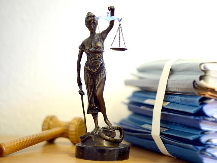 Eine Justitiafigur steht zwischen Aktenordnern und einem Richterhammer. Foto: Volker Hartmann/dpa/Archivbild