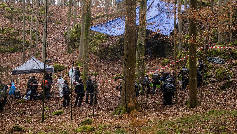 Polizisten suchen ein Gebiet im Wald ab, an dem zuvor menschliche Knochen in einer Felsspalte gefunden worden sind.