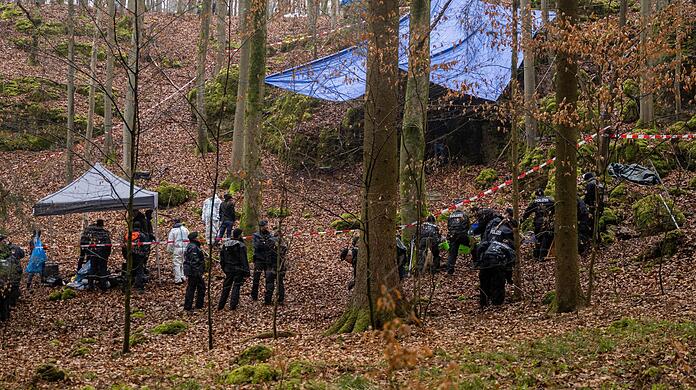Polizisten suchen ein Gebiet im Wald ab, an dem zuvor menschliche Knochen in einer Felsspalte gefunden worden sind.
