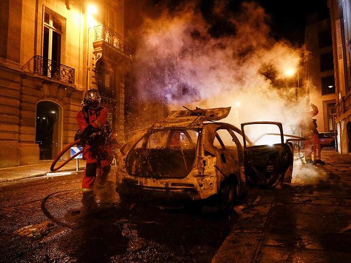 Feuerwehrmänner löschen ein brennendes Auto in der Nähe der Champs-Elysées.