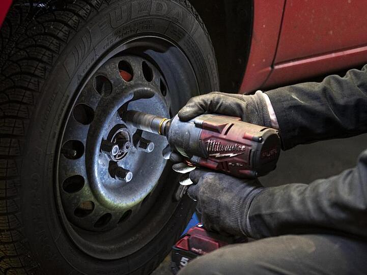 Andreas Lemmer, Automechaniker und Besitzer seiner Werkstatt, schraubt den Reifen eines Autos ab. Foto: Fabian Sommer/dpa