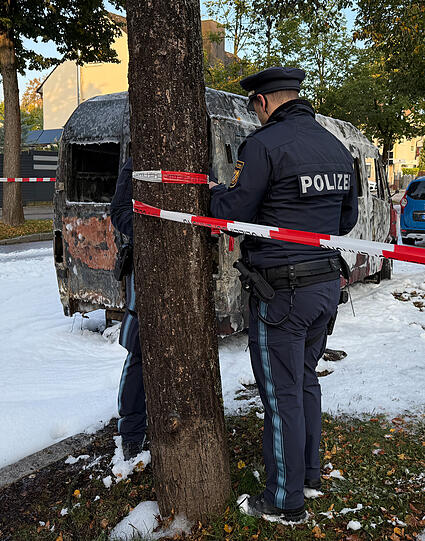 Ein Polizist bringt Absperrband an.
