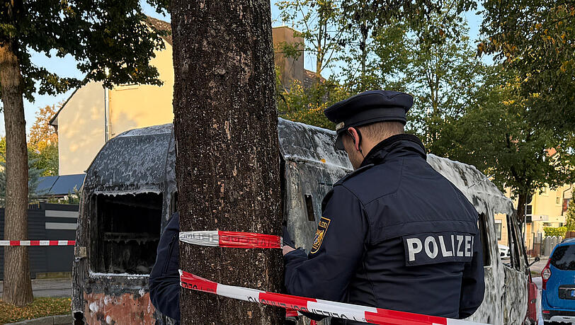 Ein Polizist bringt Absperrband an. Ein Polizist bringt Absperrband an.