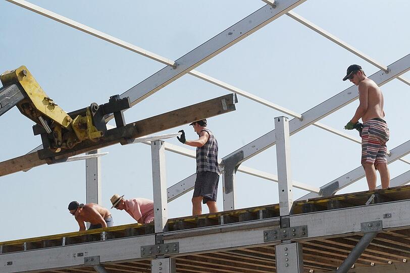 Bauarbeiter arbeiten in der Hitze auf dem Oktoberfestgelände.