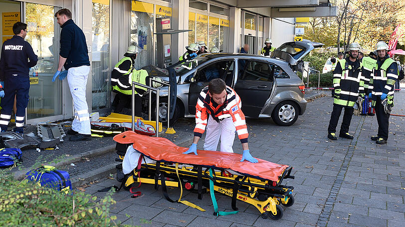 Nach dem Unfall in Solln: Helfer ziehen das Auto aus dem Schaufenster.