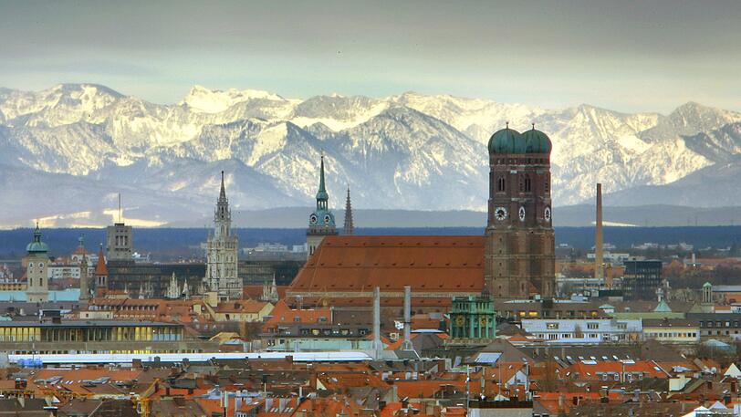 München: Die Frauenkirche steht vor den schneebedeckten Alpen.