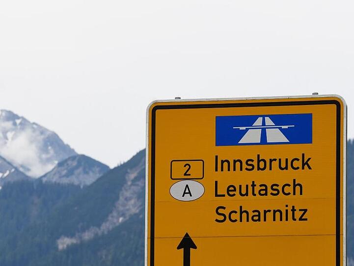 Ein Schild zeigt auf der Landstraße den Weg Richtung Innsbruck in Österreich. Foto: Angelika Warmuth/dpa/Archivbild