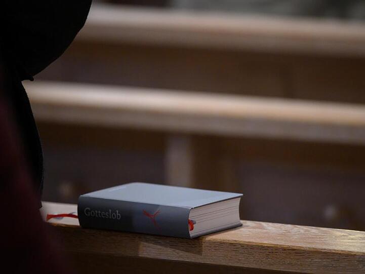 Ein Gesangbuch liegt während eines Gottesdienstes auf einer Bank. Foto: Sebastian Gollnow/dpa/Symbolbild
