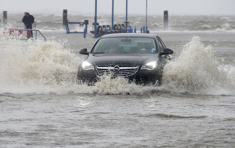 Ein Auto fährt in Dagebüll (Schleswig-Holstein) über den teilweise überfluteten Anleger.