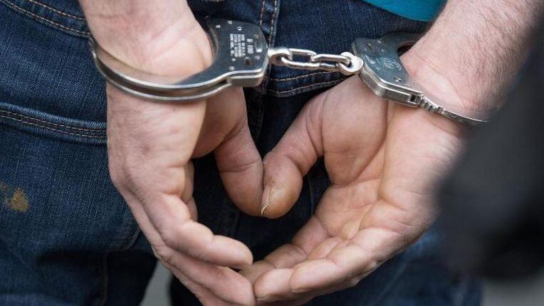 Ein Mann wird in Handschellen abgeführt. Foto: Boris Roessler/dpa/Archivbild