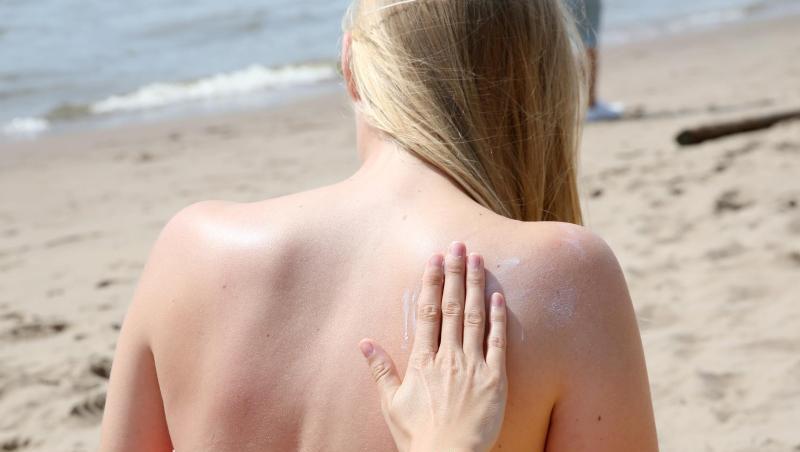 Eine junge Frau wird am Strand mit Sonnencreme eingerieben. Eine junge Frau wird am Strand mit Sonnencreme eingerieben.