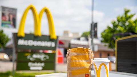 Eine McDonald's To-go-Tüte und ein dazugehöriger To-go-Becher stehen vor einer Tübinger McDonald's Filiale.