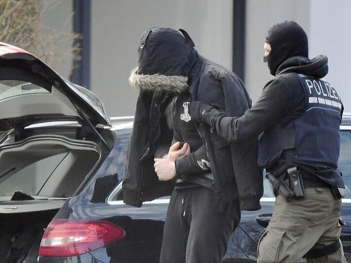 Eine Person wird von einem maskierten Polizisten in den Bundesgerichtshof in Karlsruhe gebracht.