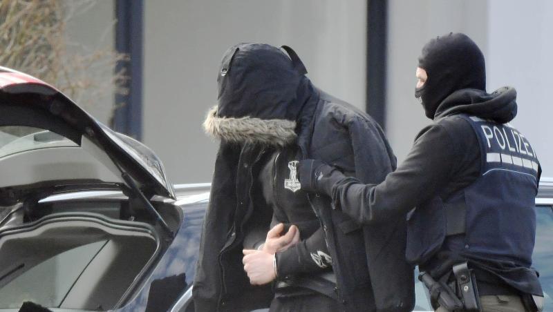 Eine Person wird von einem maskierten Polizisten in den Bundesgerichtshof in Karlsruhe gebracht. Eine Person wird von einem maskierten Polizisten in den Bundesgerichtshof in Karlsruhe gebracht.