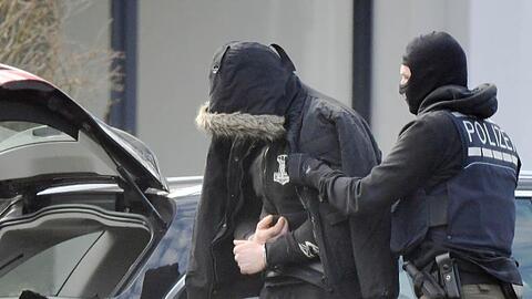 Eine Person wird von einem maskierten Polizisten in den Bundesgerichtshof in Karlsruhe gebracht.