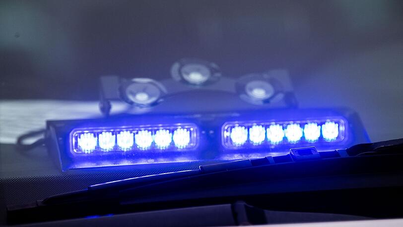 Ein Blaulicht leuchtet unter der Frontscheibe eines Einsatzfahrzeugs der Polizei.