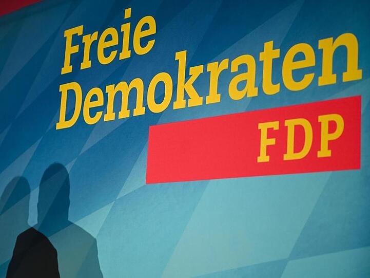 Der Schatten eines Parteimitglieds vor dem Logo der FDP. Foto: Nicolas Armer/dpa/Archivbild