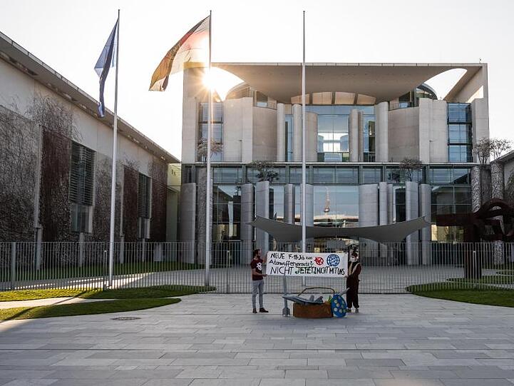 Zwei Demonstranten stehen bei einer Protestaktion gegen die Anschaffung neuer Kampfflugzeuge durch die Bundesregierung vor dem Kanzleramt.