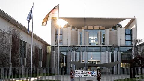Zwei Demonstranten stehen bei einer Protestaktion gegen die Anschaffung neuer Kampfflugzeuge durch die Bundesregierung vor dem Kanzleramt.