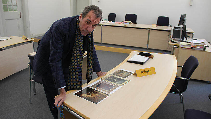 Im Gerichtssaal: Galerist Andreas Baumgartl mit Farbkopien der vier Bilder, die bei einer Reinigung beschädigt worden sein sollen.