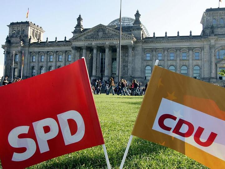 SPD- und CDU-Parteifähnchen vor dem Reichstag in Berlin. Foto: Gero Breloer/dpa/Archivbild