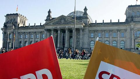 SPD- und CDU-Parteifähnchen vor dem Reichstag in Berlin. Foto: Gero Breloer/dpa/Archivbild