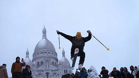 Ein Mann springt mit seinen Skiern den H&uuml;gel bei der Basilika Sacre-Coeur im franz&ouml;sischen Paris hinunter.
