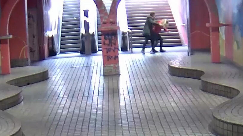 Ein junger Mann greift an der U-Bahnhaltestelle "Viehofer Platz" hinterrücks eine junge Frau an. Mit dem Überwachungsvideo aus dem das Bildschirmfoto stammt, sucht die Poilizei nach zwei Tätern, die die junge Frau am 13.04.2018 in Essen mit einer Flasche angegriffen haben.