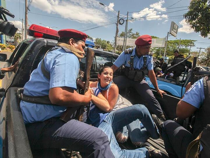 Polizisten sitzen mit festgenommenen Demonstranten auf der Ladefläche eines Fahrzeuges in Managua.