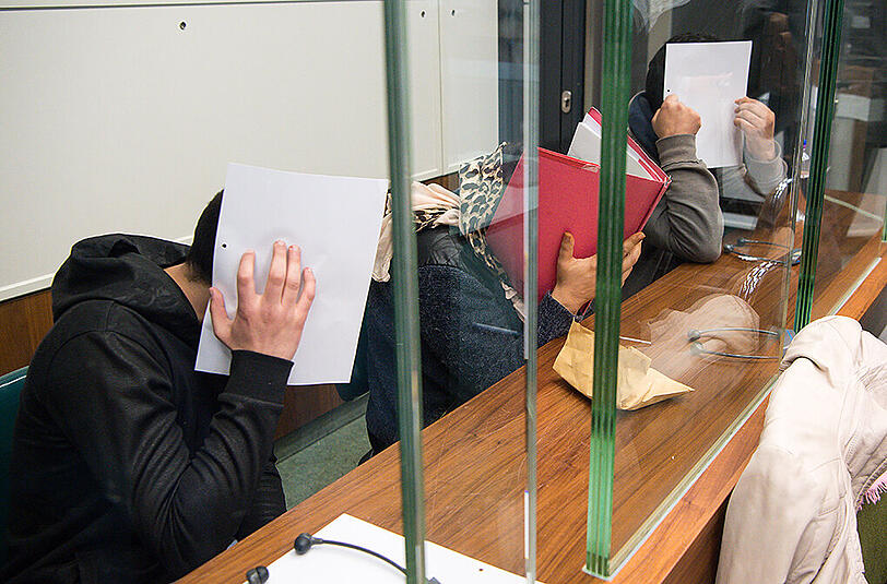 Die drei Angeklagten, die von Rumänien aus Taschendiebstähle in Berlin organisiert haben sollen, sitzen vor dem Landgericht in Berlin-Moabit. Foto: Bernd von Jutrczenka