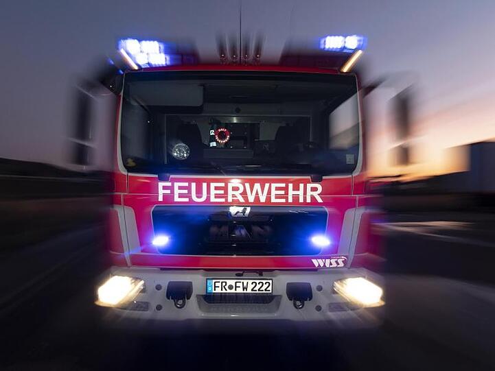 Ein Feuerwehrfahrzeug steht mit eingeschaltetem Blaulicht im Sonnenuntergang auf einer Straße. Foto: Patrick Seeger/dpa/Archivbild