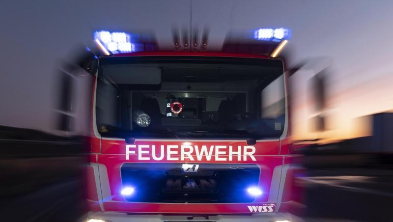 Ein Feuerwehrfahrzeug steht mit eingeschaltetem Blaulicht im Sonnenuntergang auf einer Straße. Foto: Patrick Seeger/dpa/Archivbild