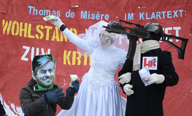 Drei kostümierte Demonstranten protestieren gegen die Münchner Sicherheitskonferenz.