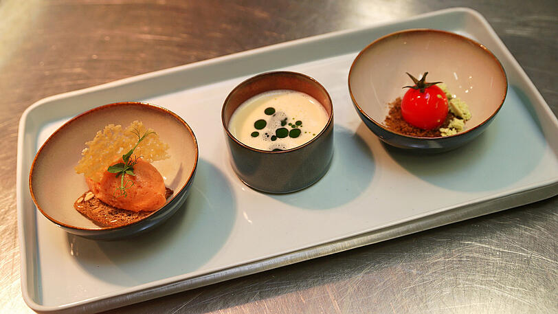 Eine weiße Tomatenmousse, zur Tomate geformt, mit Tomatensorbetgelee bestrichen und einem aufgesetzten Strünklein. Eine heiße, weiße Tomatensuppe. Und geeistes Tomatensorbet.
