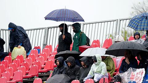 Fans sitzen während des Freien Trainings mit Regenschirmen auf der Tribüne.