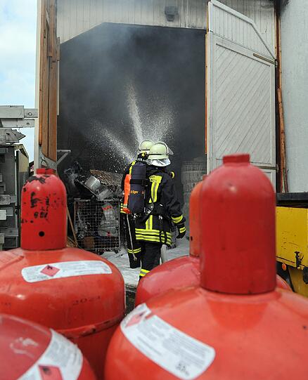 Feuerwehrleute löschen am Freitag in Karlsfeld (Oberbayern) ein brennendes Gebäude. Aus unbekannter Ursache war in dieser Halle eines Dachdeckerbetriebes ein Brand ausgebrochen.