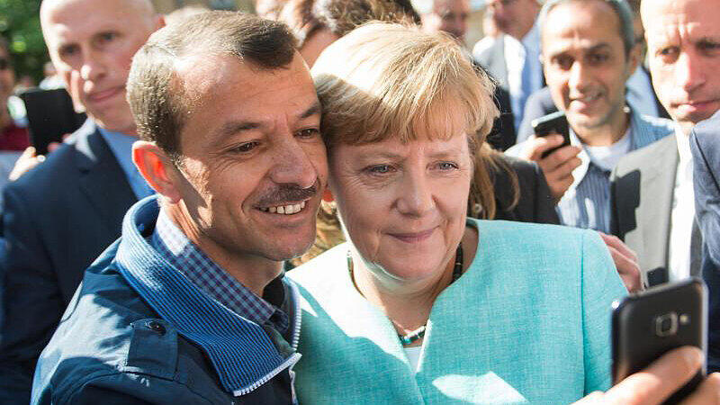 Kanzlerin Angela Merkel lässt sich für ein Selfie zusammen mit einem Flüchtling fotografieren.